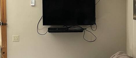 Una habitación con un televisor de pantalla plana montado, una puerta de madera y un sofá estampado.
