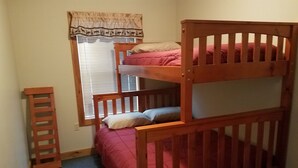 A bunk bed with a ladder, a window with blinds, and a carpeted floor.