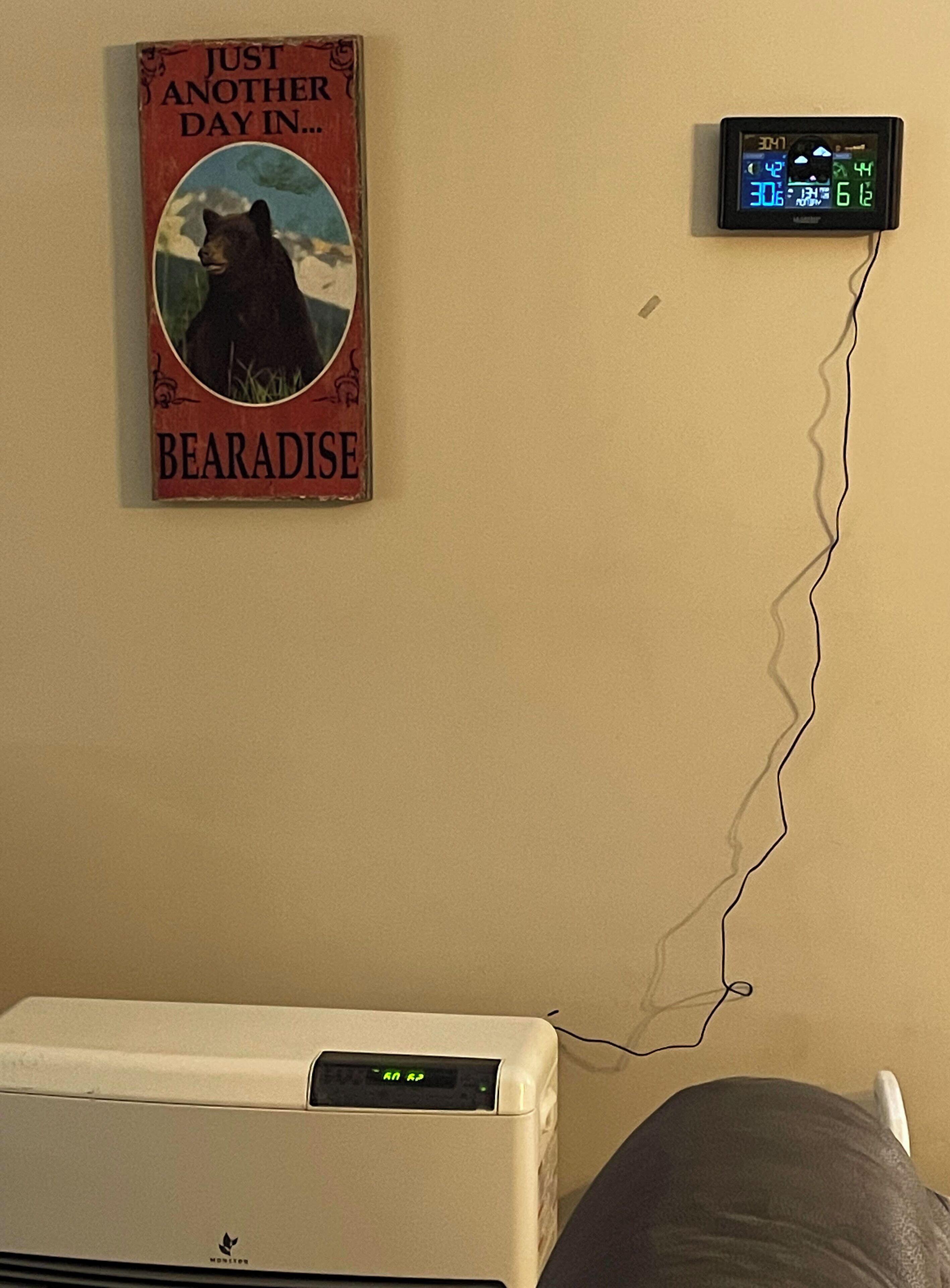 A wall-mounted thermostat and a vintage poster of a bear.
