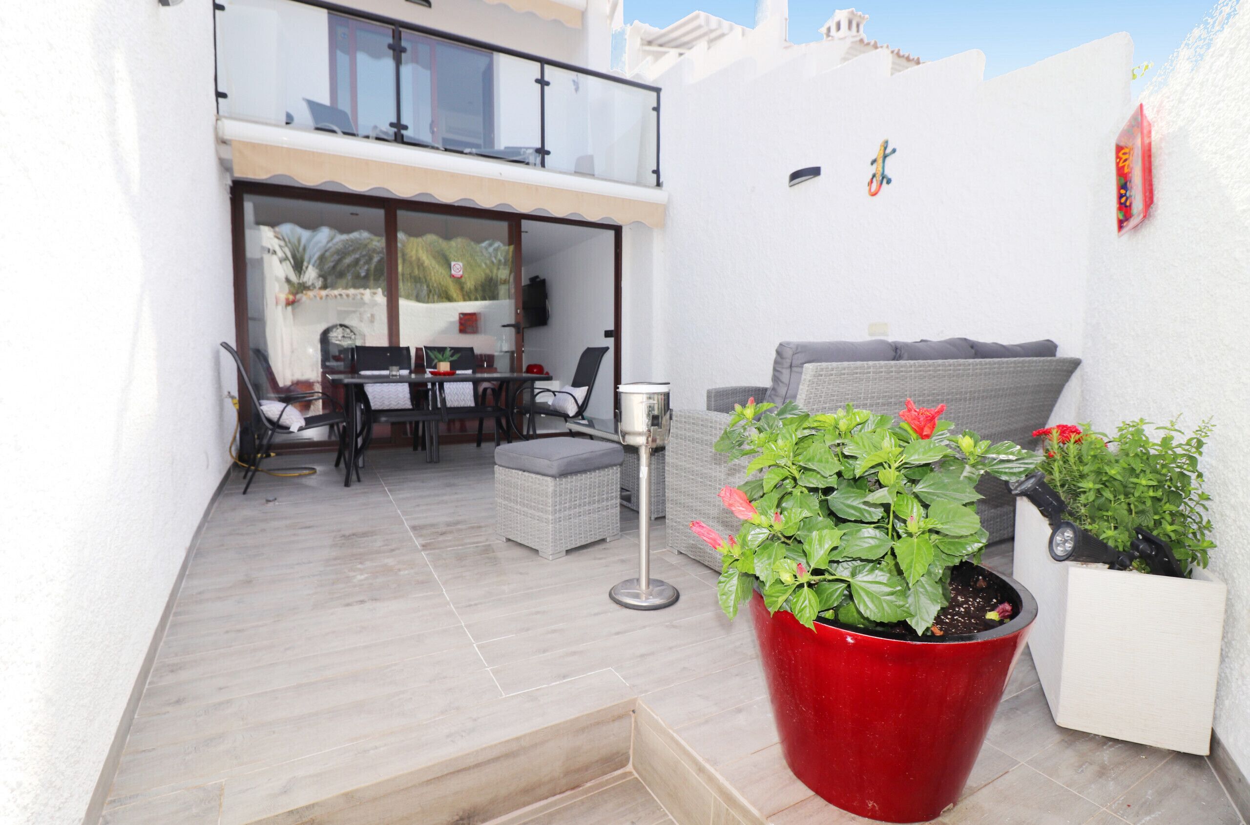 A patio area with a dining table and chairs, a sofa, and potted plants.