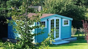 Une petite construction d’un seul étage, dotée d’un toit à pignon, entourée d’une pelouse bien entretenue et d’un feuillage dense.