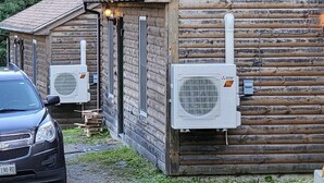 En timmerstuga med två luftkonditioneringsaggregat monterade på ytterväggen.