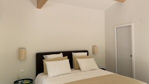 Une chambre à coucher avec un lit, une table de chevet, une lampe et une porte.