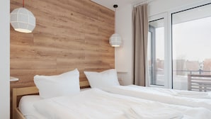 A hotel room with two beds, wooden headboard, large window, and pendant lights. - Modern apartment near the beach with beach chair (Grömitz)