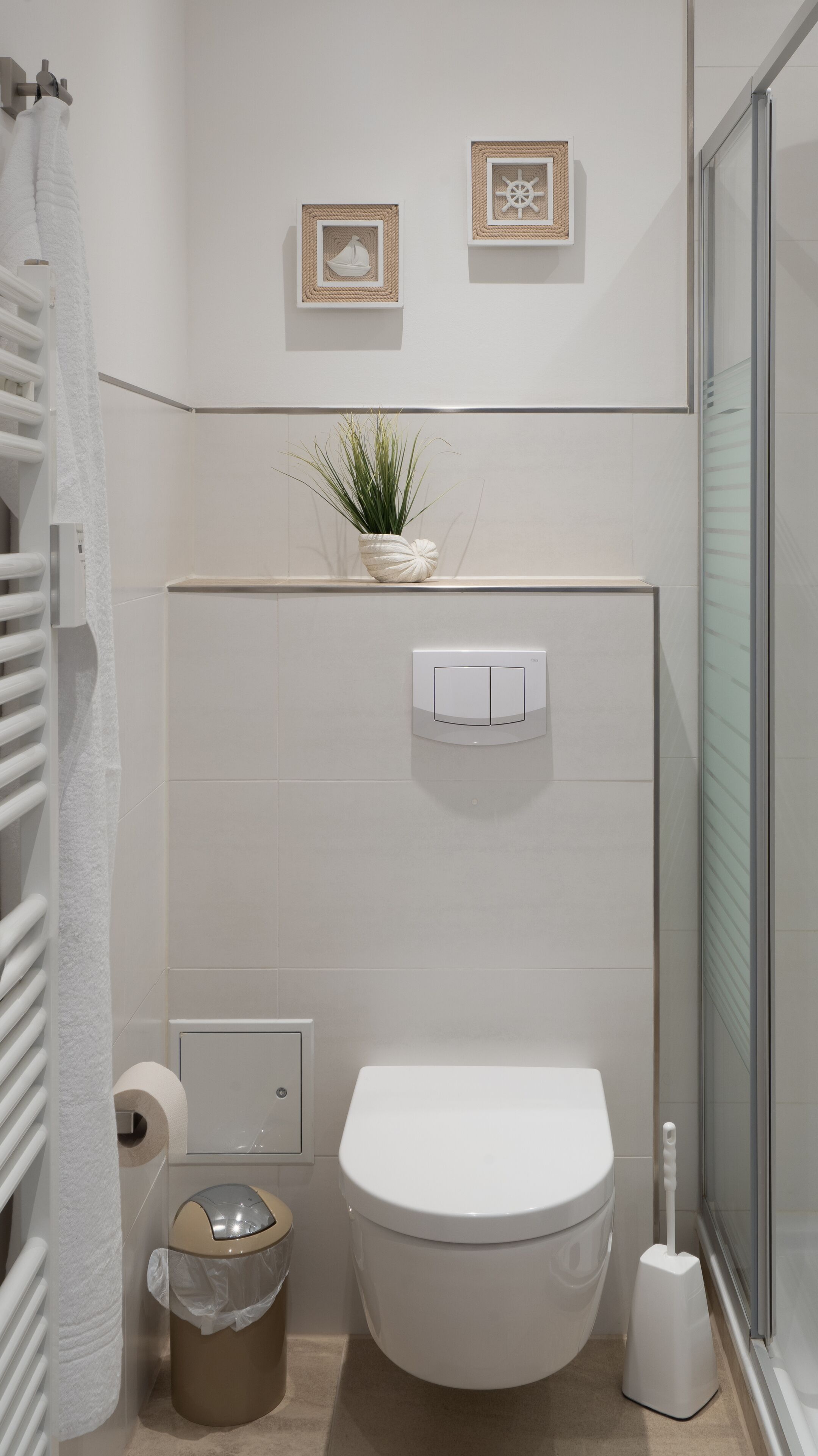 Een moderne badkamer met toilet, prullenbak, toiletrolhouder en douche.