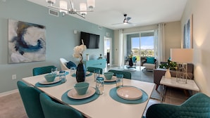 Un comedor moderno con sillas color turquesa, una mesa blanca y vajilla azul y blanca.