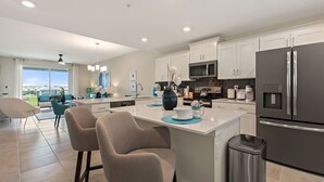 Una cocina moderna con armarios blancos, electrodomésticos de acero inoxidable y una isla central con asientos.