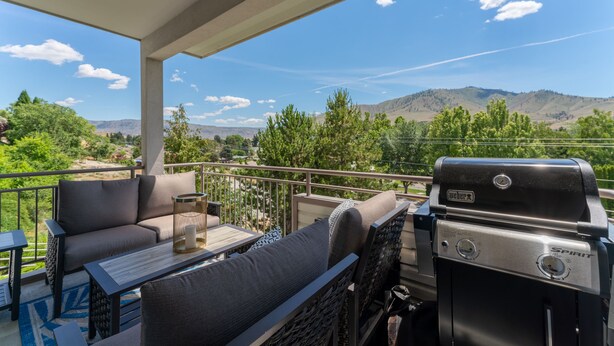 A balcony with outdoor furniture, a Weber Spirit grill, and a scenic view of mountains and greenery. - Park Pointe A201 - Community Pool/Hot tub (Chelan)