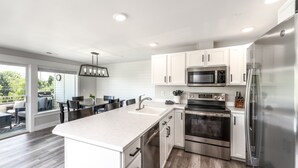 A modern kitchen with white cabinetry, stainless steel appliances, and a large island. - Park Pointe A201 - Community Pool/Hot tub (Chelan)