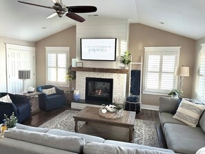A living room with a fireplace, two sofas, a coffee table, and a ceiling fan.