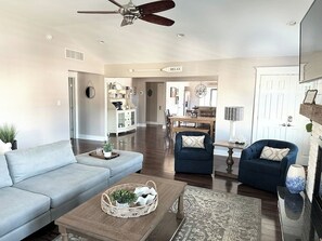 A spacious living room with a sofa, armchairs, a coffee table, and a fireplace.