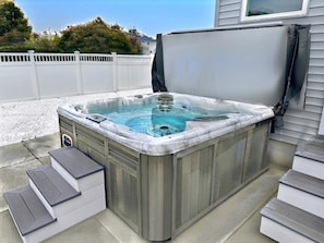 Ein Whirlpool mit Stufen, umgeben von einem weißen Zaun und einem Haus.