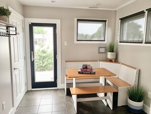 Une cuisine compacte avec un banc intégré, une petite table à manger et une fenêtre donnant sur un espace verdoyant.