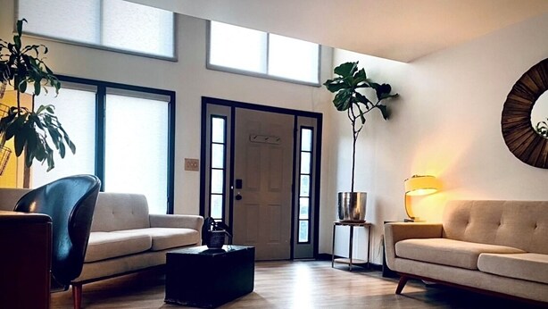 A spacious living room with a large window, a sofa, a coffee table, and a side table with a lamp. - Townhouse Located Near Frontier Park and the Capitol Building (Cheyenne)