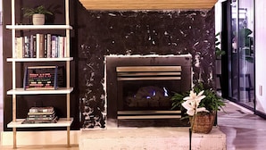 A modern living room with a fireplace, a bookshelf, and decorative plants. - Townhouse Located Near Frontier Park and the Capitol Building (Cheyenne)
