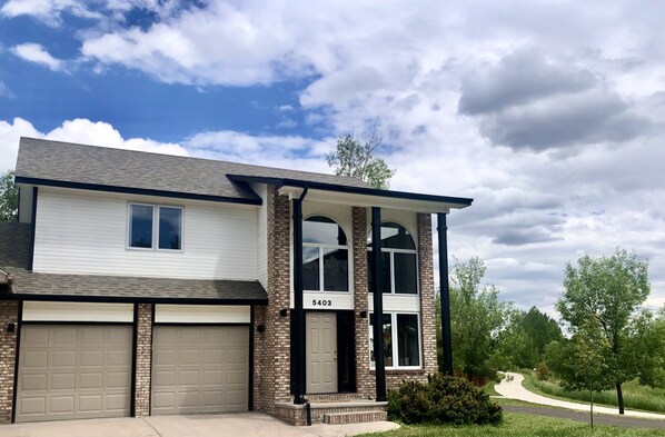 A two-story house with a garage, a brick facade, and a clear sky.