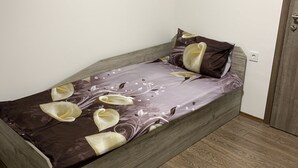 Un lit simple avec une couvre-lit à motifs floraux et deux oreillers, une tête de lit en bois et un plancher en bois.