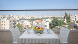 Un balcone con un tavolo apparecchiato per due, con una ciotola di frutta e due bicchieri.