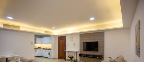 A modern living room with a sofa set, a coffee table, and a flat-screen TV mounted on the wall.