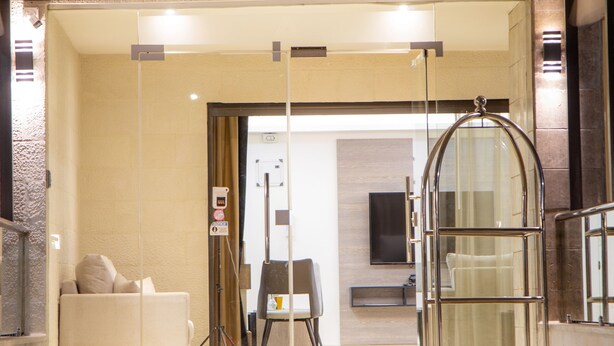L'ingresso di un hotel chiamato "TRIPLE A", con una porta in vetro, una reception e un'area salotto con divano e poltrone.