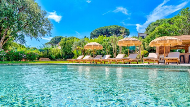 A poolside area with lounge chairs and umbrellas, surrounded by lush greenery and trees. - Large charming Bastide- private pool- Air conditioning- WIFI-1.2 km from St Tropez-Vue Mer (GASSIN)