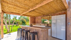 An outdoor kitchen with a wooden bar, stools, and a refrigerator. - Large charming Bastide- private pool- Air conditioning- WIFI-1.2 km from St Tropez-Vue Mer (GASSIN)