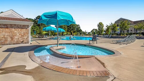 Une piscine avec un jacuzzi, des chaises longues et des parasols.