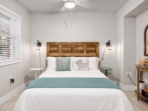 A bedroom with a bed, a ceiling fan, bedside tables, and a nightstand. - Waterfront Key West Retreat |Heated Pool| Dock|BBQ (Marco Island)