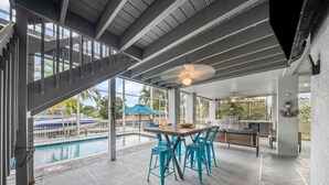 Un espace extérieur abrité comprenant une piscine, une table à manger avec des chaises et un escalier.