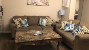 A living room with a brown sofa set, patterned throw pillows, a wooden coffee table, and a painting of a beach scene on the wall. - Stunning entire house in Channel Islands Marina (Oxnard)