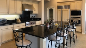 A modern kitchen with a central island, stainless steel appliances, and bar stools. - Stunning entire house in Channel Islands Marina (Oxnard)