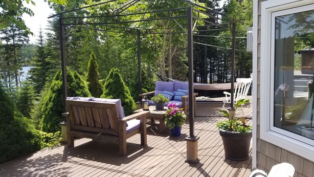A wooden deck with a wooden bench, a sofa, and a table with potted plants.