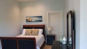 A bedroom with a bed, a nightstand, a lamp, and a painting on the wall.