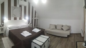 Une chambre à coucher avec un lit, des tables de chevet, un canapé et une petite table avec une lampe.