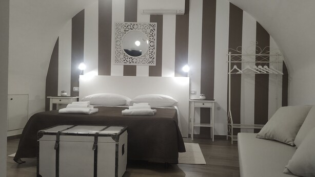Une chambre d’hôtel avec un lit, une armoire, un miroir et une valise.