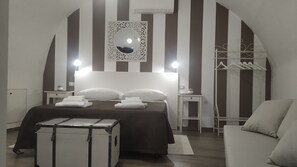 Habitación de hotel con cama, armario, espejo y maleta.