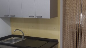 Une cuisine avec des armoires blanches, un évier en acier inoxydable et un plan de travail noir.