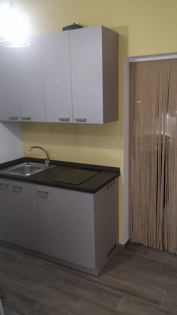 Una cocina con armarios blancos, un lavamanos de acero inoxidable y una encimera negra.