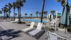 A poolside area with lounge chairs and umbrellas, palm trees, and a view of the ocean. - 5 STAR BEACHFRONT 2BR/2BA • Dunes of Panama D505 • Nov & Dec Snowbird Available! (Panama City Beach)