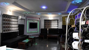 A modern lounge area with a flat-screen TV, seating, and a wine rack. - The Agore Hotels and Suites (Lekki)