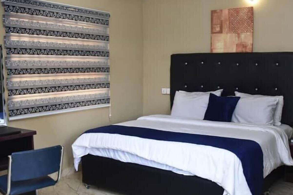 A hotel room with a bed, a desk, and a chair.