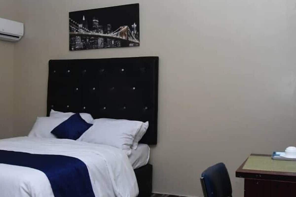A hotel room with a bed, a desk, and a chair.