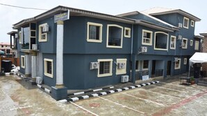 A multi-story building with a flat roof, air conditioning units, and a tiled ground floor. - The Agore Hotels and Suites (Lekki)