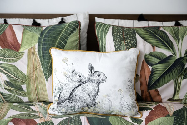 Ein Bett mit einem blumigen Überwurf und einem Kissen mit einer Hasen-Illustration.