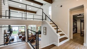 Un interior amplio con una escalera que conecta dos plantas, una sala de estar con vistas y un pasillo que conduce a un armario.