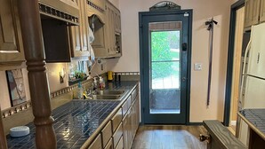 A kitchen with wooden cabinets, a tiled backsplash, and a wooden floor. - Perfect relaxing lake retreat for hosting a gathering. Quiet with no neighbors. (Westminster)