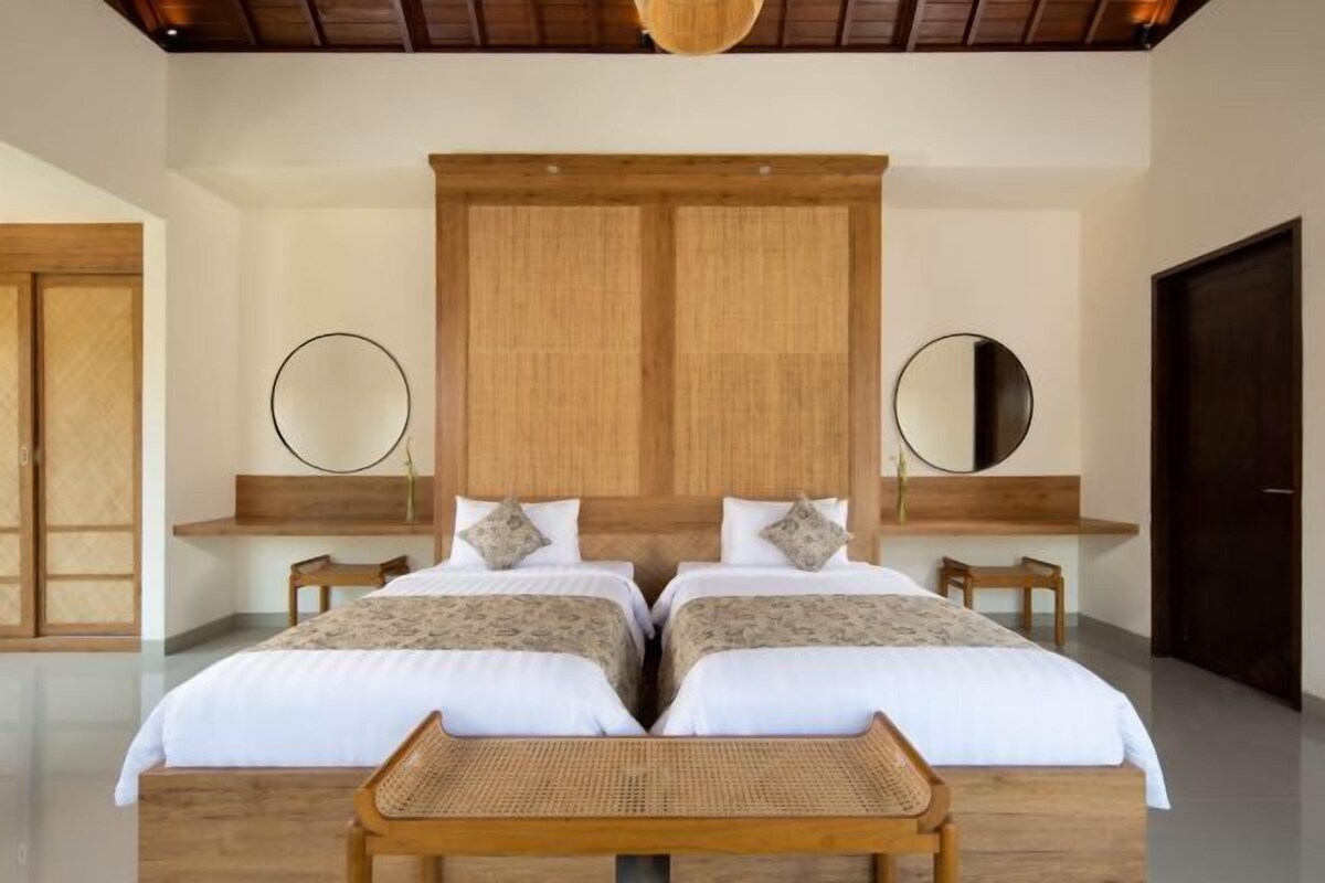 Ein Doppelzimmer mit zwei Betten, Holzkopfteilen, Nachttischen und einem großen Spiegel an der Wand.