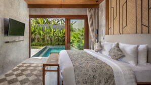 A bedroom with a large bed, a television, and a view of a swimming pool. - Agrapana Beach Villa (Sukawati)