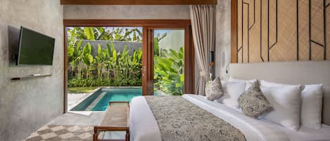 Quarto com uma cama grande, televisão e vista para uma piscina.