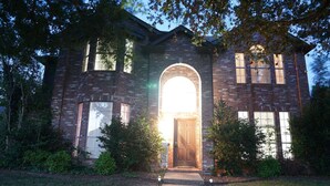 A two-story brick house with a prominent arched entrance, multiple windows, and a well-maintained front yard. - Remodeled luxury with Proximity (Lewisville)